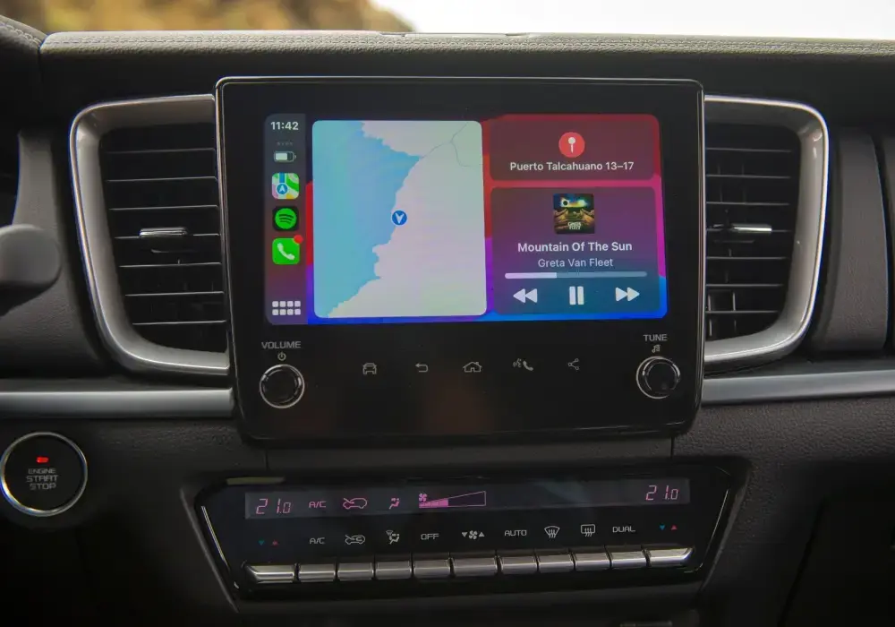 Interior de camioneta de aventura mostrando pantalla multimedia, climatizador bi-zona y conectividad Android Auto.