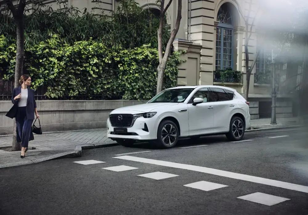 Auto híbrido enchufable Mazda CX-60 conducido por la ciudad.