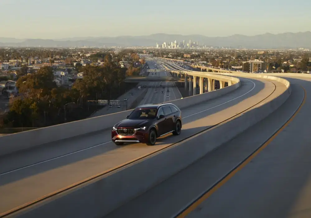 SUV Mazda CX‑90 híbrido en movimiento en ruta con curvas.